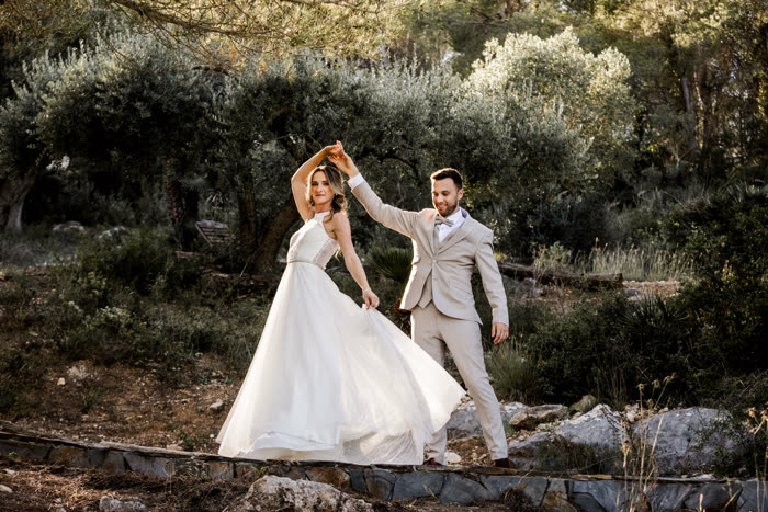 Ola and Akis twirling together among olive trees on their wedding day